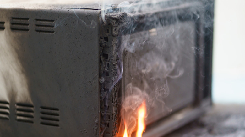 Microwave on fire with smoke all around