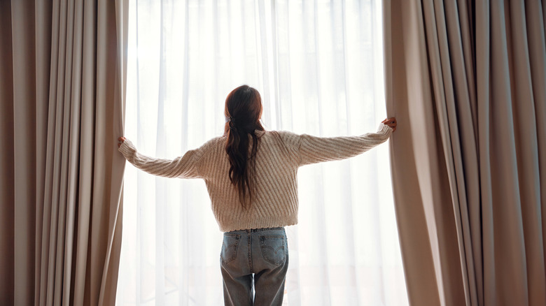 person opening curtains