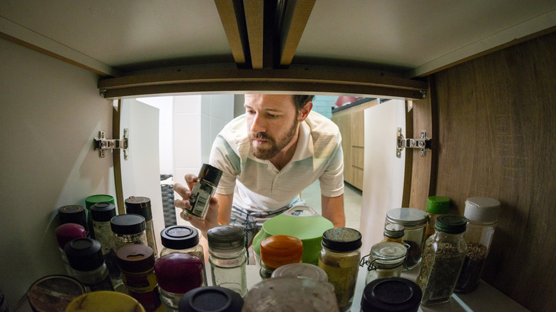 A man reaching into a deep cabinet full of spices