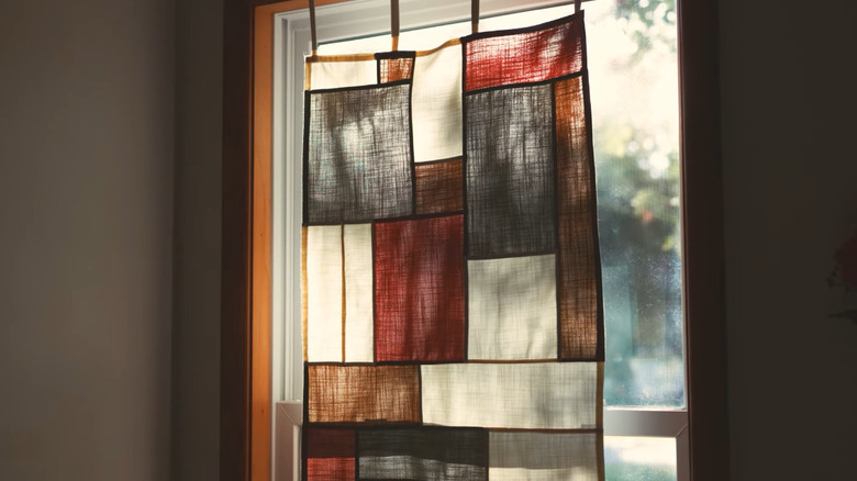 A pojagi-style curtain hanging in a window