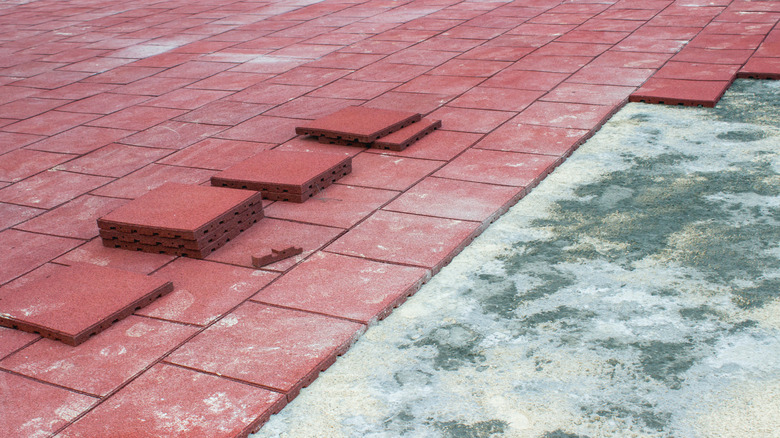 Red square rubber pavers mid-installation