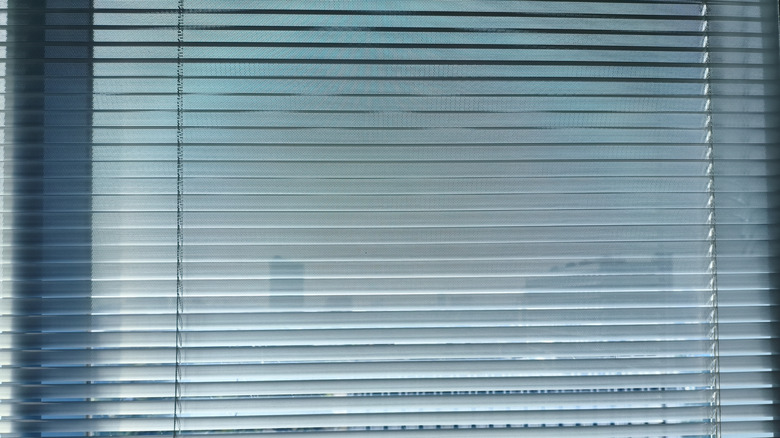 Gray aluminum blinds closed over a window