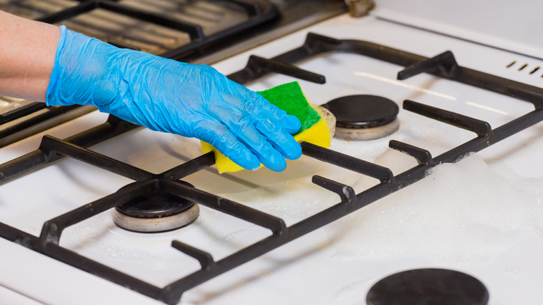person cleaning gas stove grates