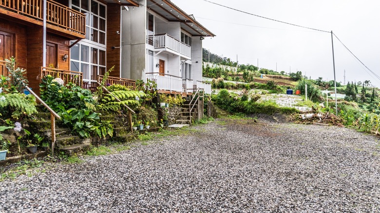 Gravel driveway in front of duplex housing units on a hill