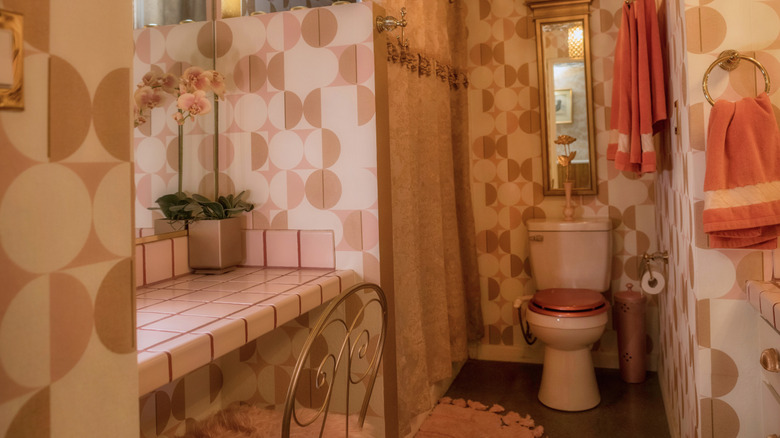 Retro-inspired bathroom with pink geometric wallpaper.
