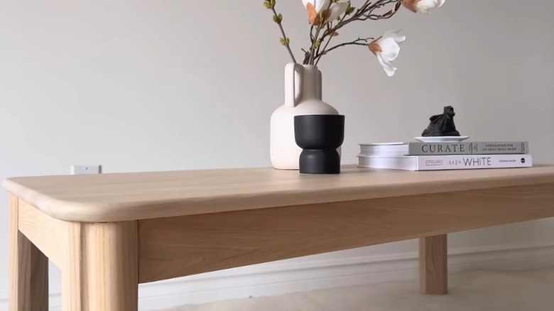 Coffee table with white oak finish holding books and modern decor