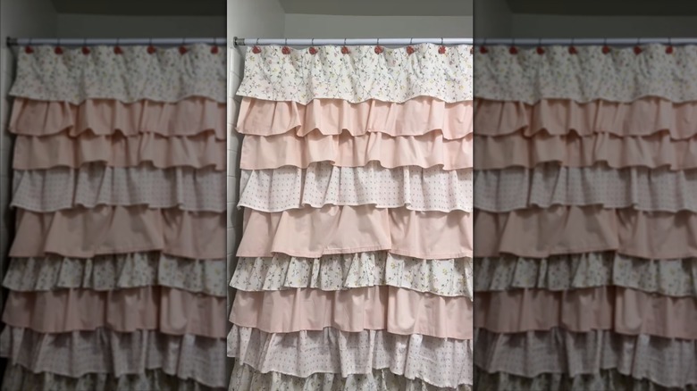 A fabric shower curtain with layers of pink, white, and floral fabric ruffles
