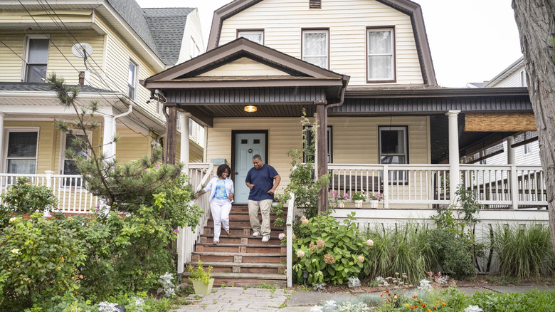 Couple walking down porch stairs during the daytime.