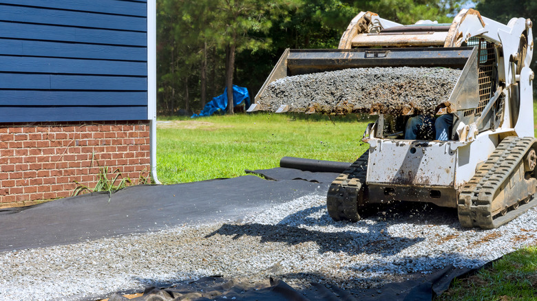 Equipment spreading crushed concrete or gravel over landscape fabric