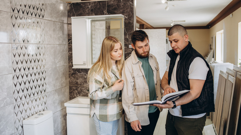 A man showing a couple options for a bathroom upgrade in a store