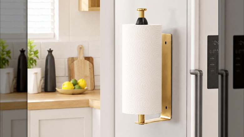 A magnetic gold paper towel holder is placed on the side of a white fridge in a kitchen.