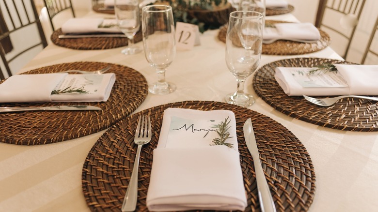 An elegant table setup with paper menus inside napkins