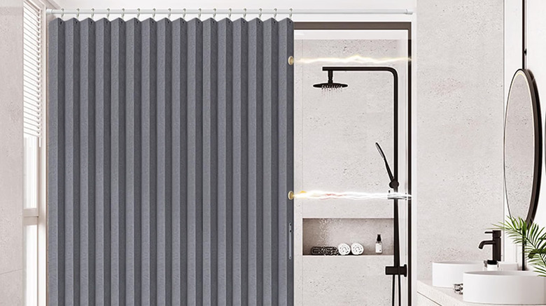 A bathroom with a magnetic folding shower curtain pulled halfway across the shower/tub area