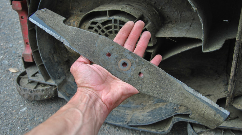 hand holding used mower blade