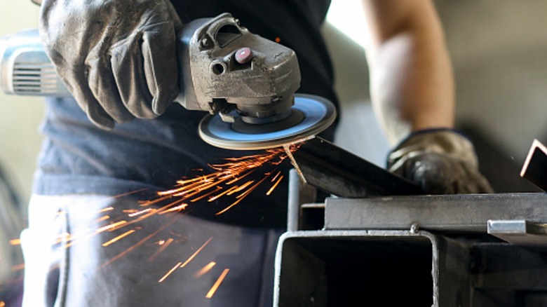 Worker grinding metal with an angle grinder