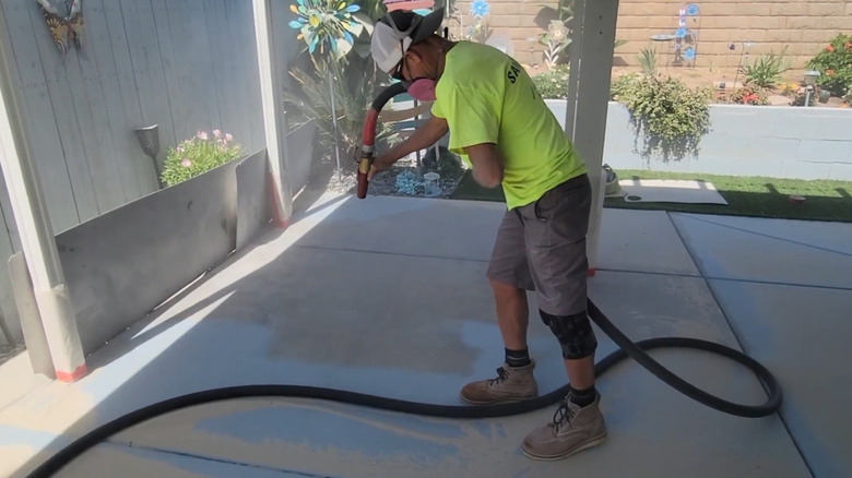 A man sandblasting a painted concrete patio