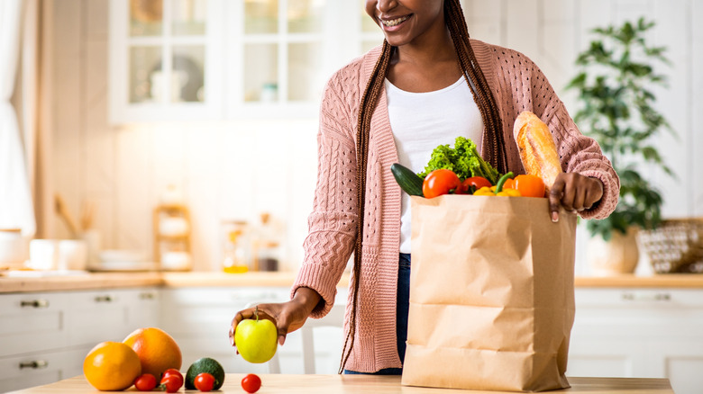 A person unloading a grocery bag of fruit in a kitchen