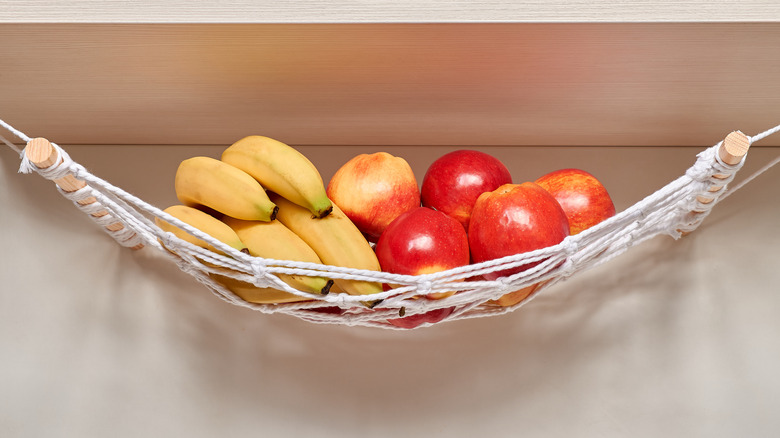 A fruit hammock filled with apples and bananas