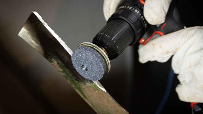 Using a drill attachment to sharpen a mower blade