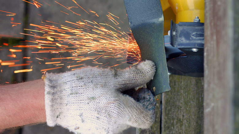 A professional sharpening a mower blade