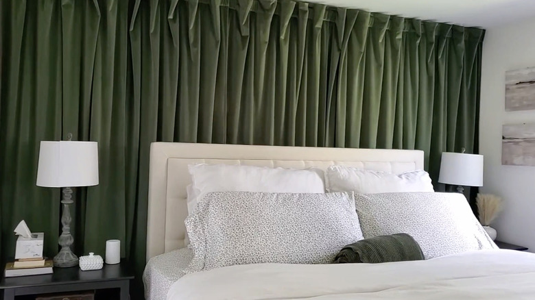 Green curtain accent wall behind a bed