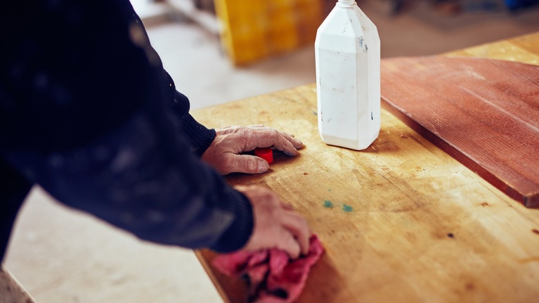 Worker rubbing bleach onto wood with a rag