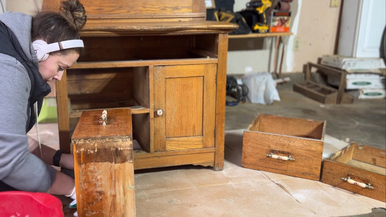 Woman disassembling an old oak cabinet