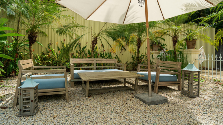 patio area with table and chair set atop gravel