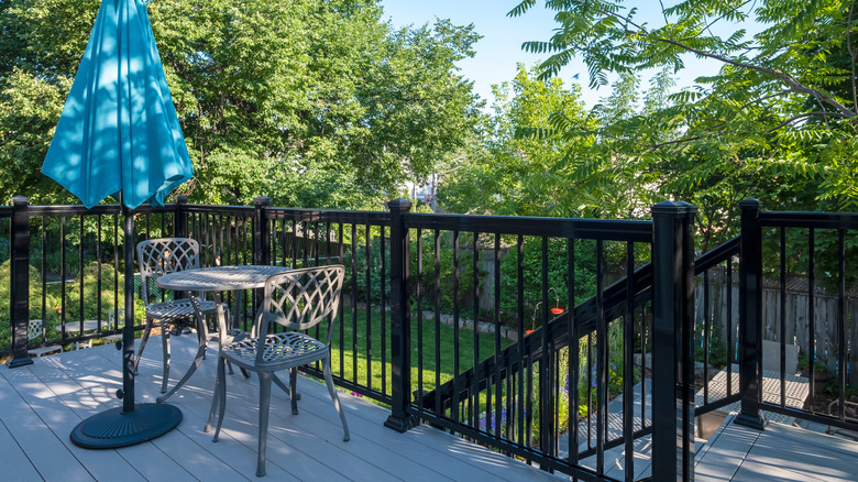 gray pvc flooring on a deck with black railings and metal cafe table set