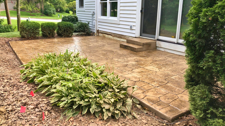 stamped concrete patio attached to porch of home with sliding glass door