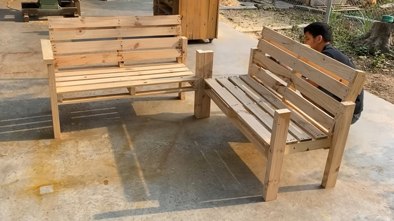 A man finished two wooden benches made from pallets