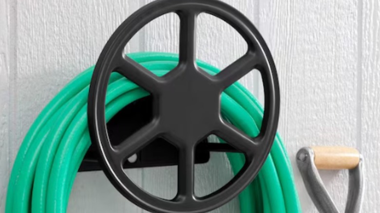 Grenn rubber hose hanging on Liberty Garden Hose Hanger