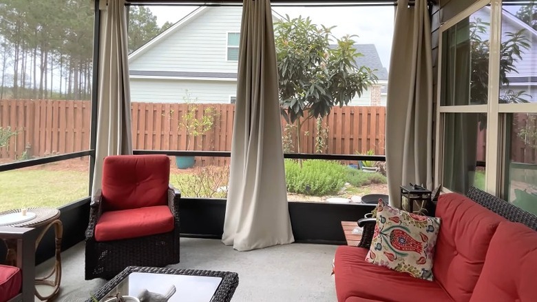 Open outdoor curtains on backyard deck with neighbor's home in view