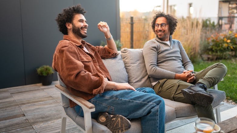 Two men chatting while sitting on a sofa on an exposed backyard deck