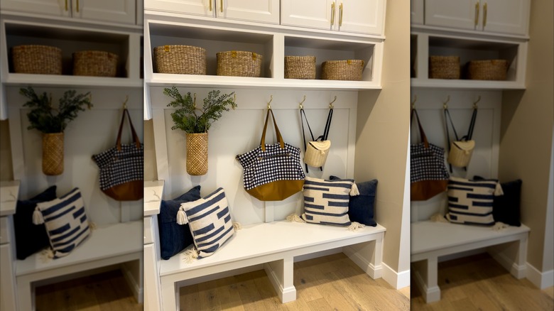 A white entryway with hooks, baskets for storage, and blue and white pillows