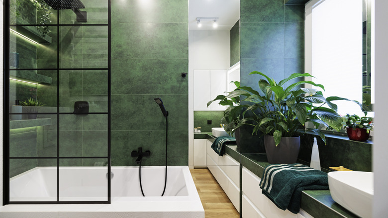 Green and white modern bathroom with framed tub screen over tub
