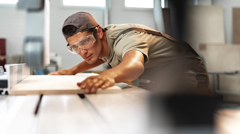 A woodworker examines a piece of wood on a table