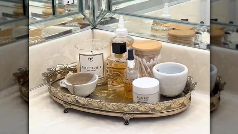 A vintage tiered tray displaying cosmetics and various perfumes in a bathroom.