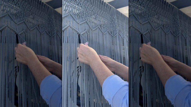 Person weaving a boho-inspired macrame panel outdoors.