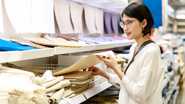 A woman is looking at placemats in a store