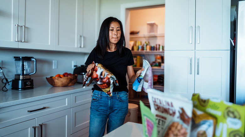A woman carrying items from an open pantry to a kitchen island