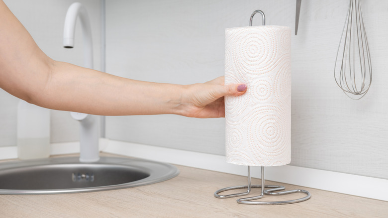hand putting paper towel roll on metal holder