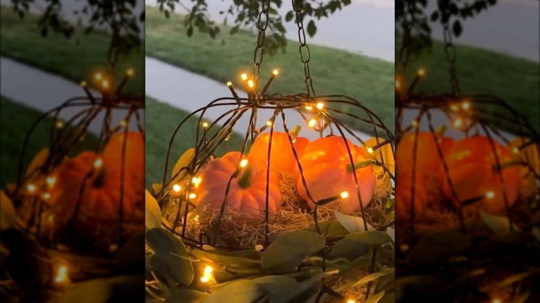 Fall porch light made from Dollar Tree hanging baskets, lights, and pumpkins