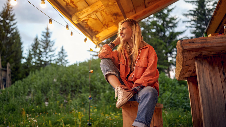 Smiling woman sitting on fall porch with lights