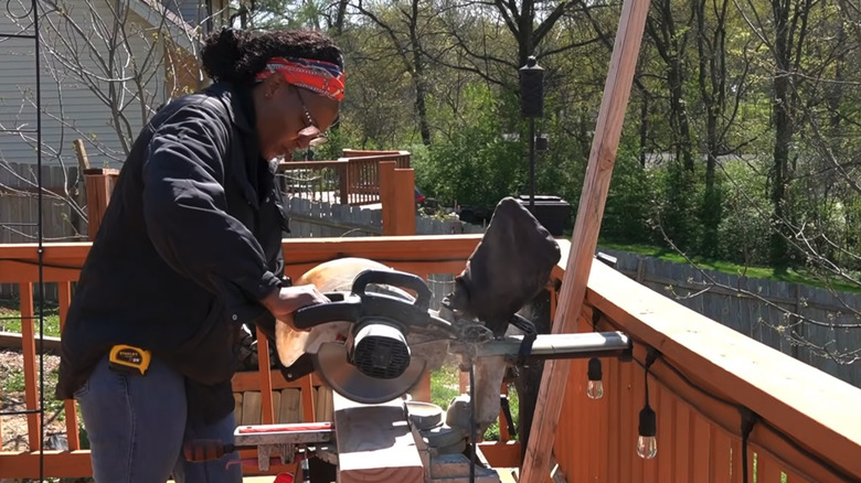 Eva Monroe using a table saw outdoors to create a wooden frame