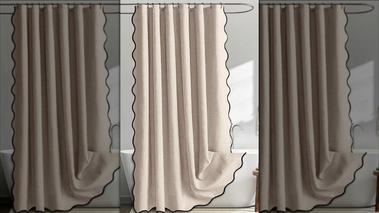 A shower curtain with a black trim hanging over a freestanding bath