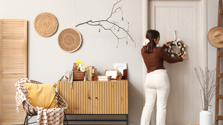 Woman adjusting a wreath on a door