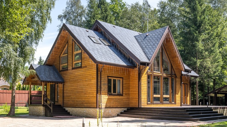 House with peaked roof and wood siding surrounded by trees