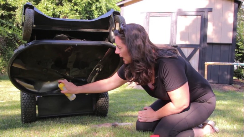 a woman spraying PAM cooking spray on her lawn mower