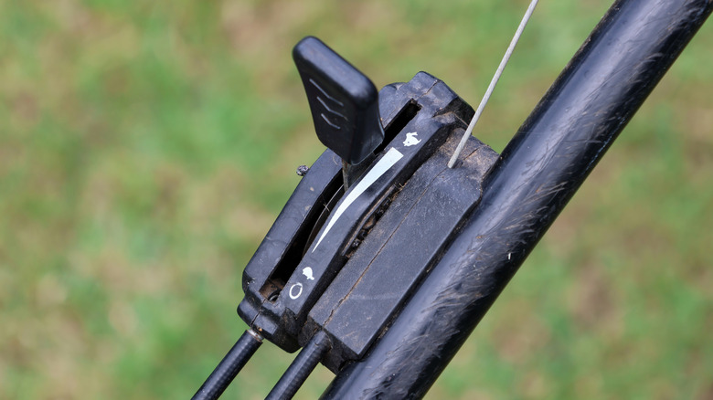 Close-up of a black throttle control lever and cable assembly on a lawn mower handlebar